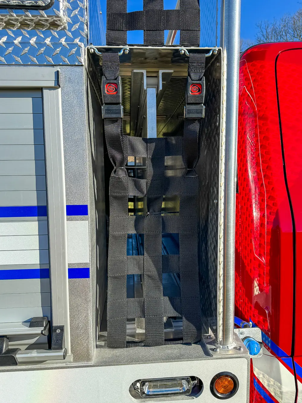 Vertical side rack behind cab with mounted red equipment packs.