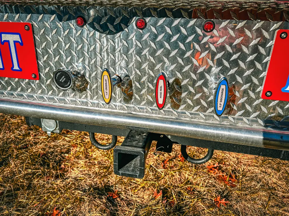 Rear diamond-plate panel close-up with labeled discharge ports.