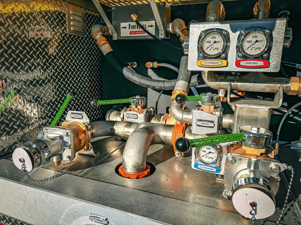 Pump plumbing close-up with gauges, valves, and pipe junctions.