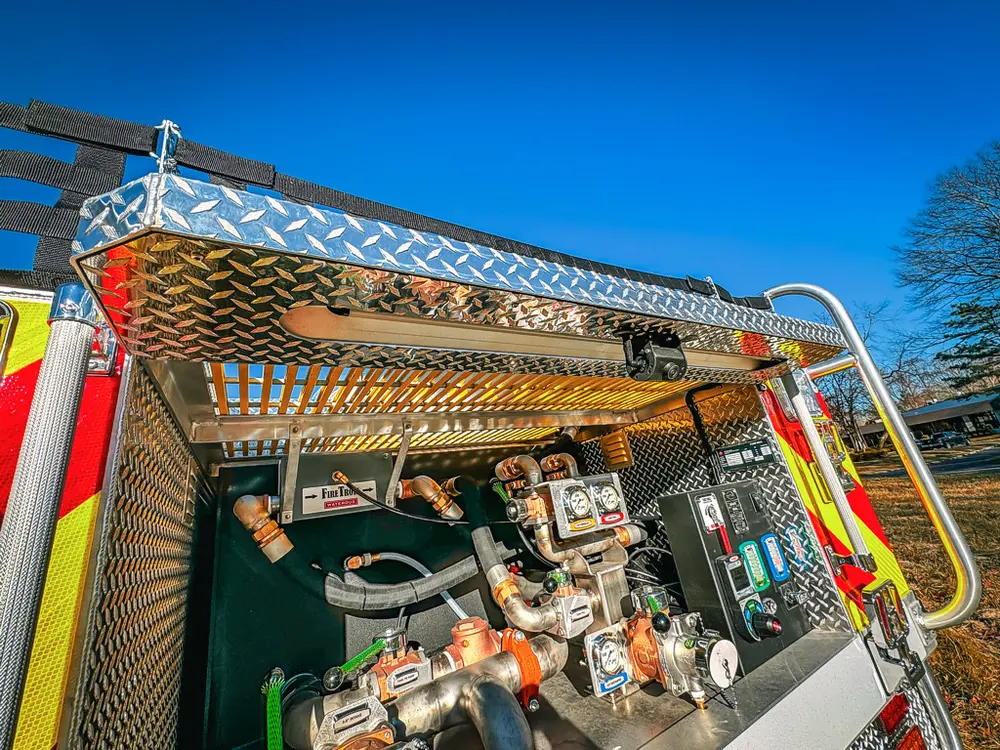 Rear pump bay view under raised hatch with controls and piping exposed.