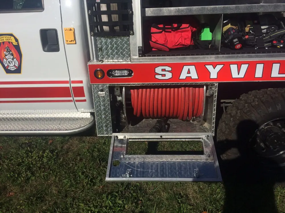 Exterior view of small fire truck showing cab, body compartments, and wheel/tire area.