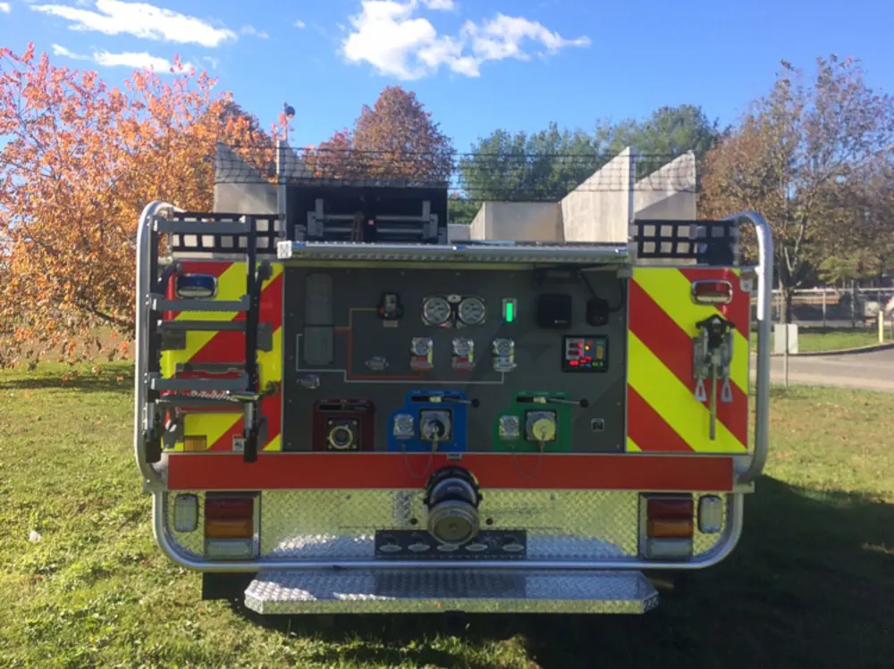 Exterior view of small fire truck showing cab, body compartments, and wheel/tire area.