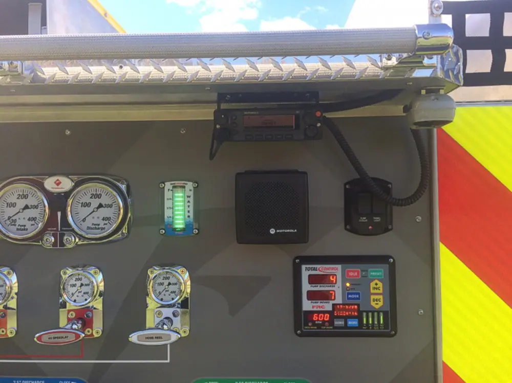 Exterior view of small fire truck showing cab, body compartments, and wheel/tire area.