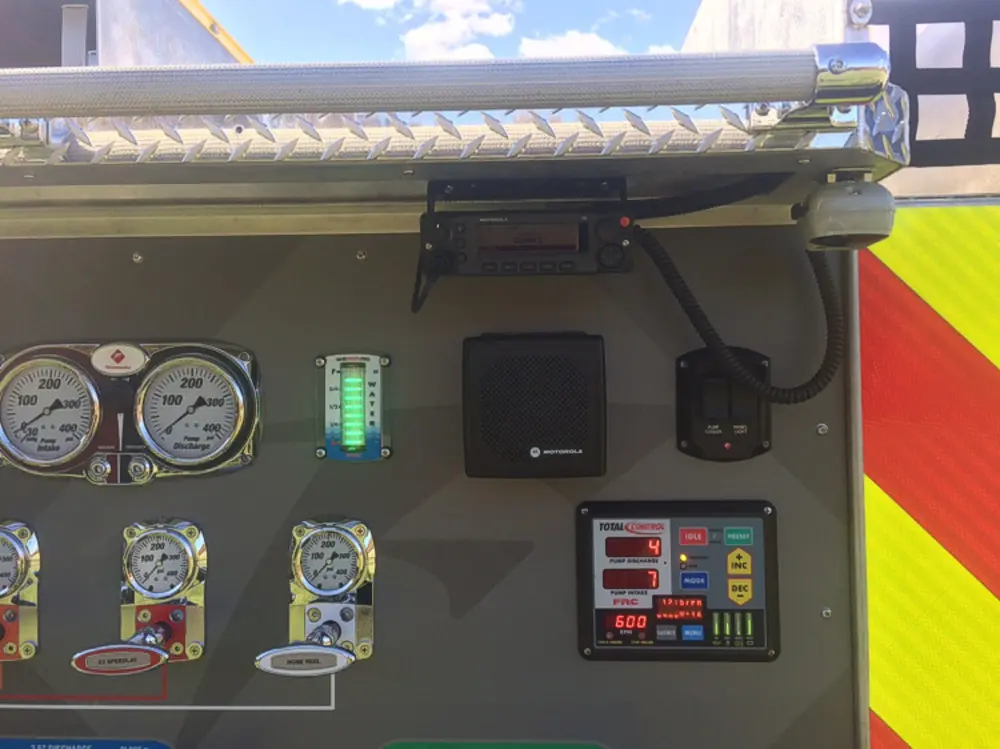 Exterior view of small fire truck showing cab, body compartments, and wheel/tire area.