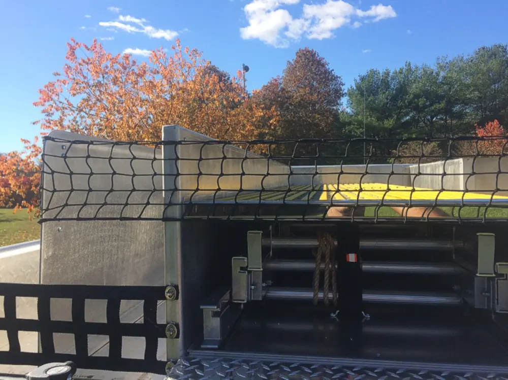Exterior view of small fire truck showing cab, body compartments, and wheel/tire area.