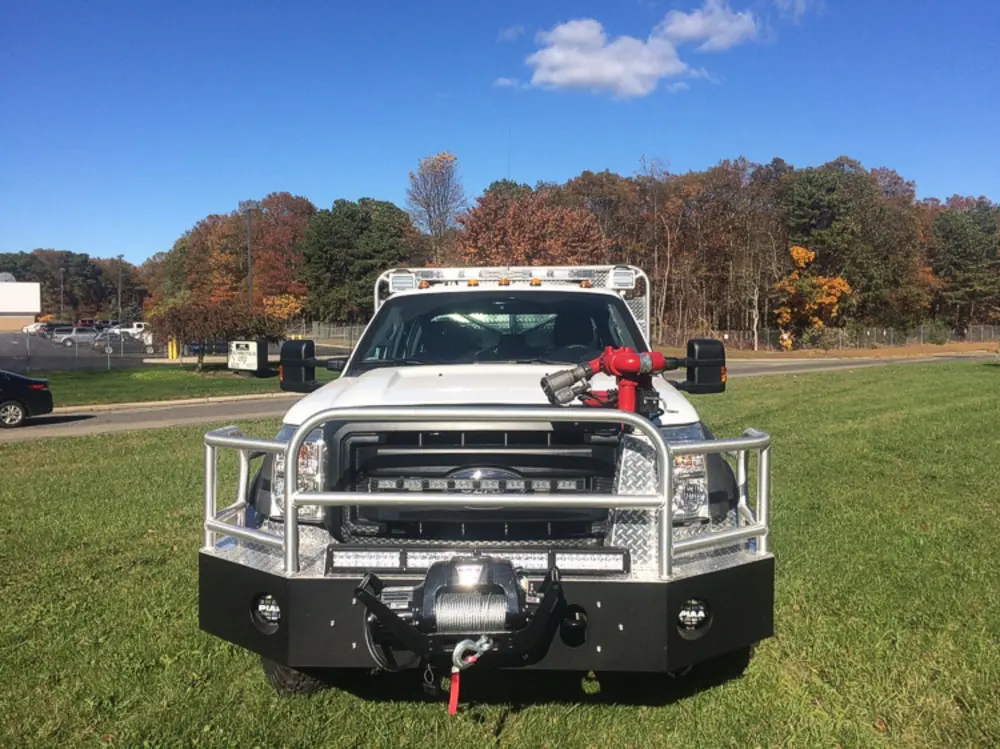 Exterior view of small fire truck showing cab, body compartments, and wheel/tire area.