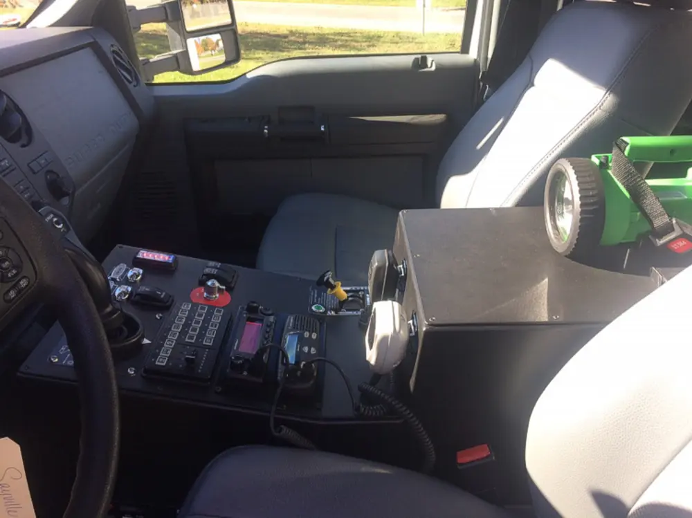Exterior view of small fire truck showing cab, body compartments, and wheel/tire area.