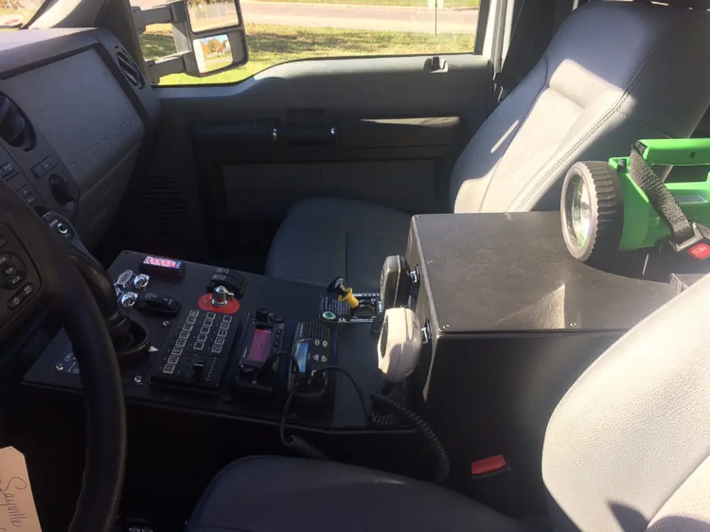 Exterior view of small fire truck showing cab, body compartments, and wheel/tire area.