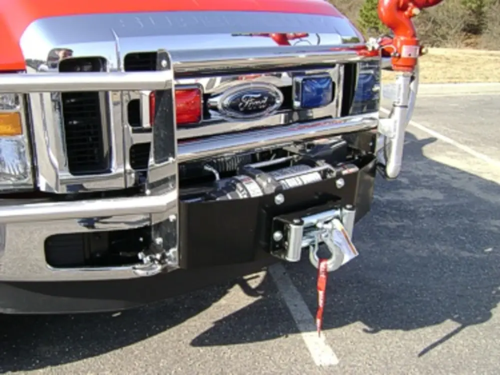 Exterior view of small fire truck showing cab, body compartments, and wheel/tire area.