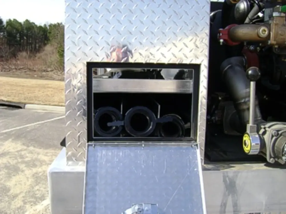 Exterior view of small fire truck showing cab, body compartments, and wheel/tire area.