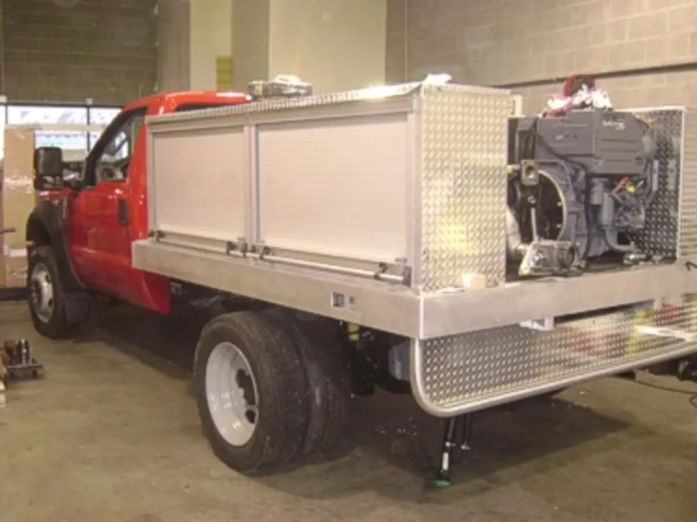 Exterior view of small fire truck showing cab, body compartments, and wheel/tire area.