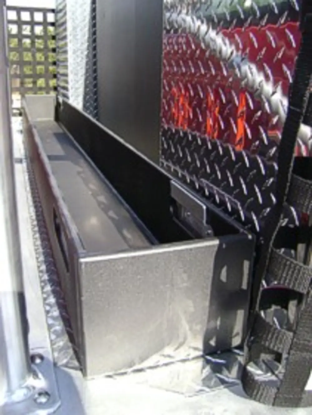 Exterior view of small fire truck showing cab, body compartments, and wheel/tire area.