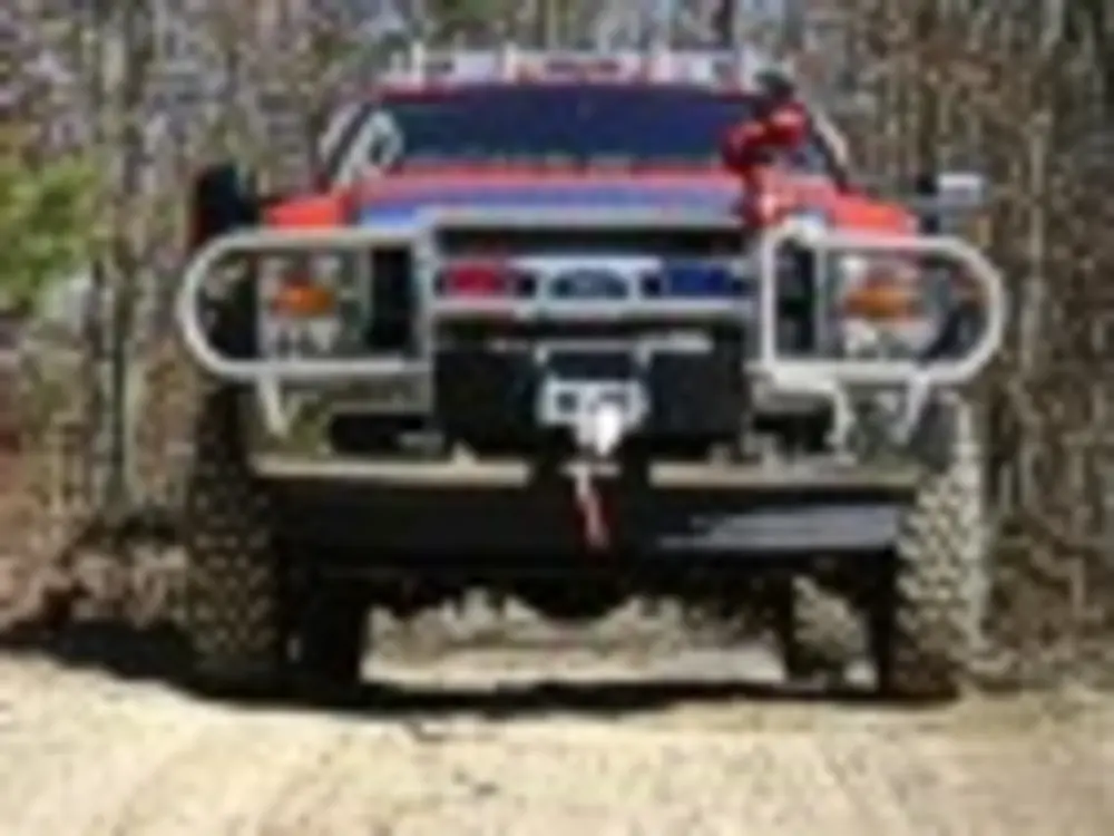 Exterior view of small fire truck showing cab, body compartments, and wheel/tire area.