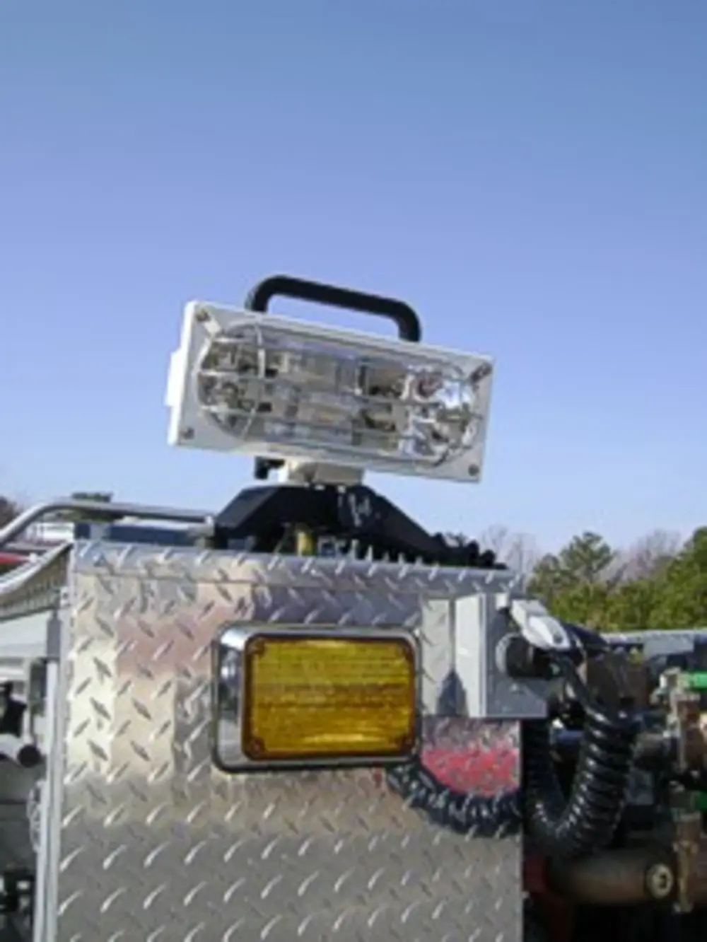 Exterior view of small fire truck showing cab, body compartments, and wheel/tire area.