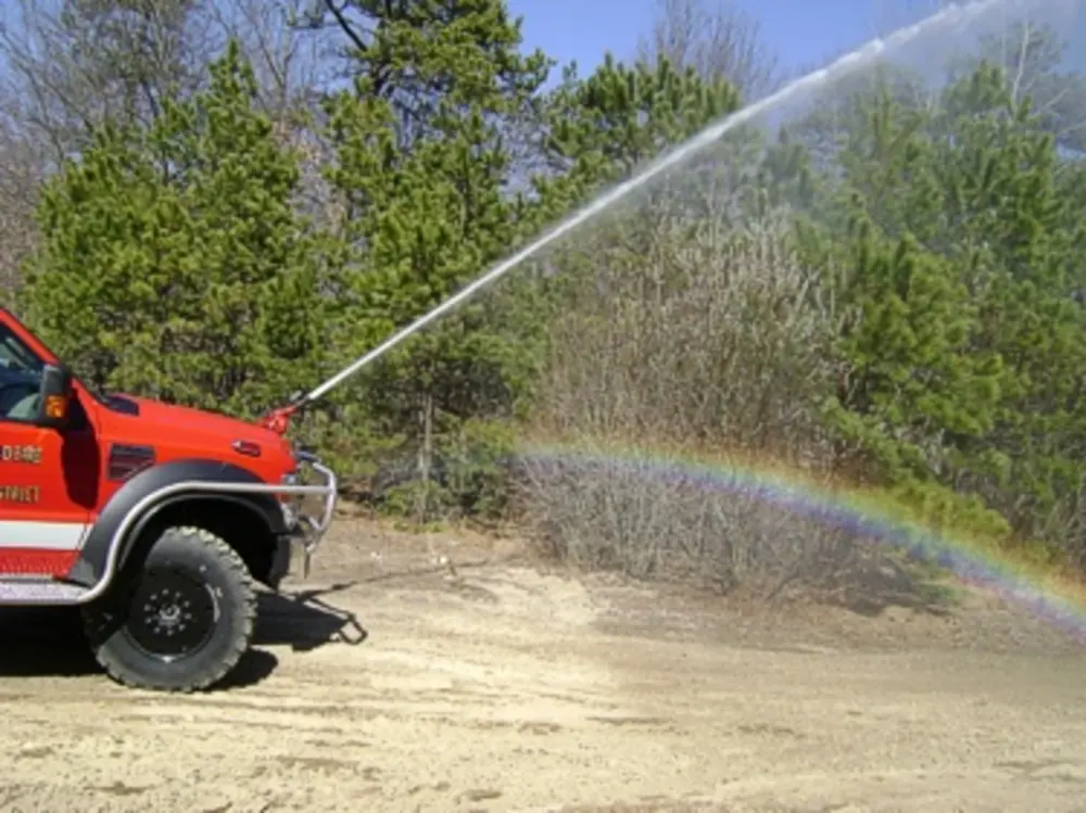 Exterior view of small fire truck showing cab, body compartments, and wheel/tire area.