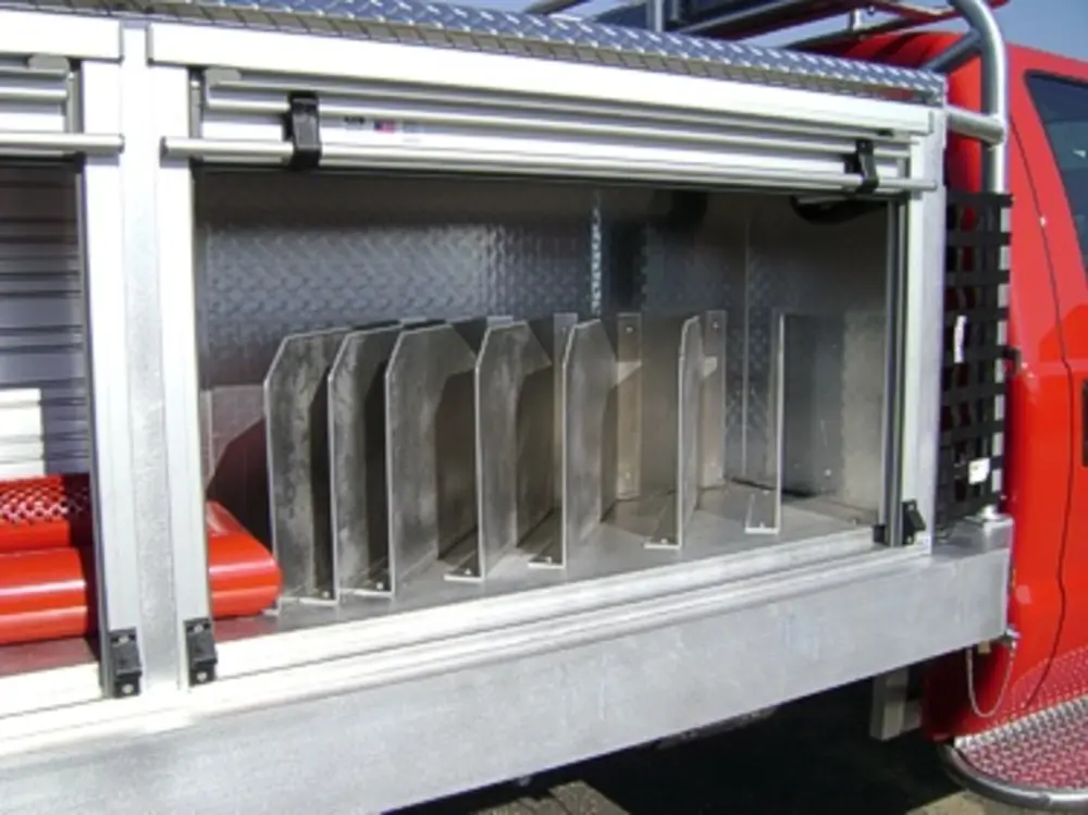 Exterior view of small fire truck showing cab, body compartments, and wheel/tire area.