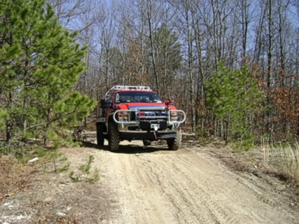 Exterior view of small fire truck showing cab, body compartments, and wheel/tire area.