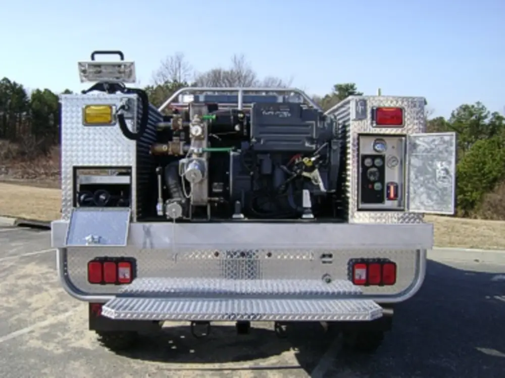 Exterior view of small fire truck showing cab, body compartments, and wheel/tire area.
