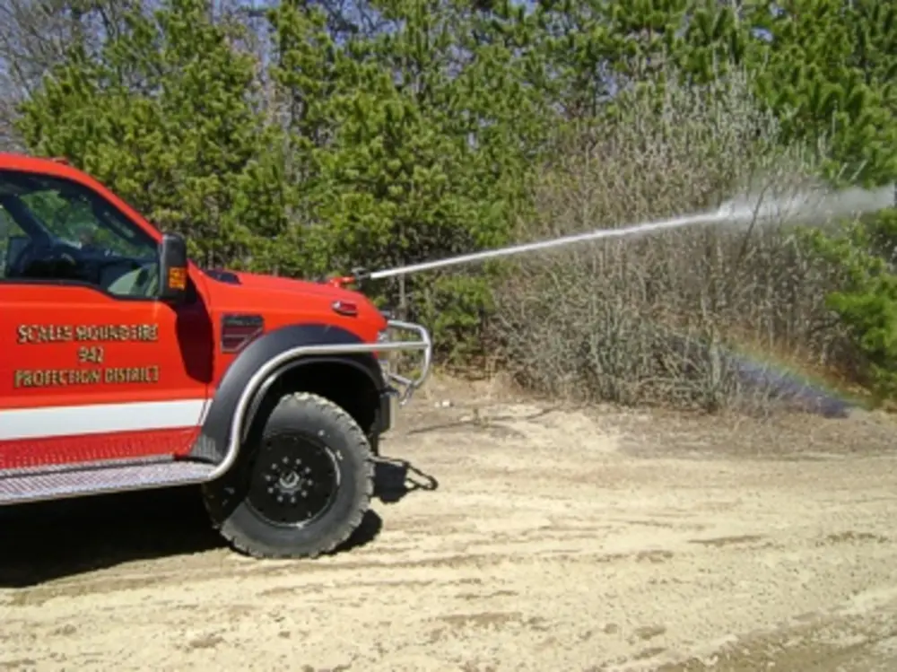 Exterior view of small fire truck showing cab, body compartments, and wheel/tire area.