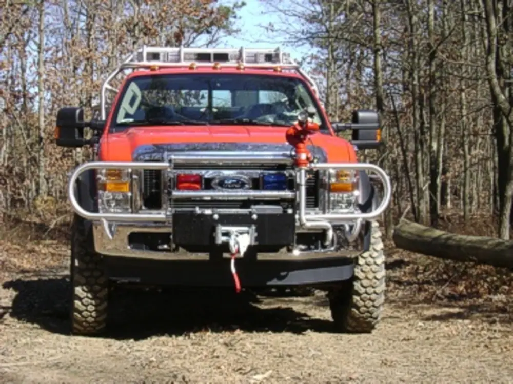 Exterior view of small fire truck showing cab, body compartments, and wheel/tire area.