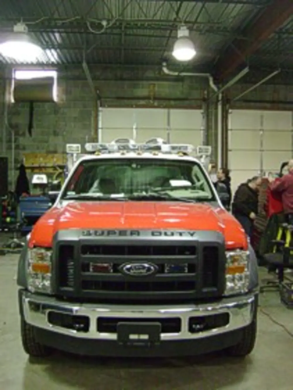 Exterior view of small fire truck showing cab, body compartments, and wheel/tire area.