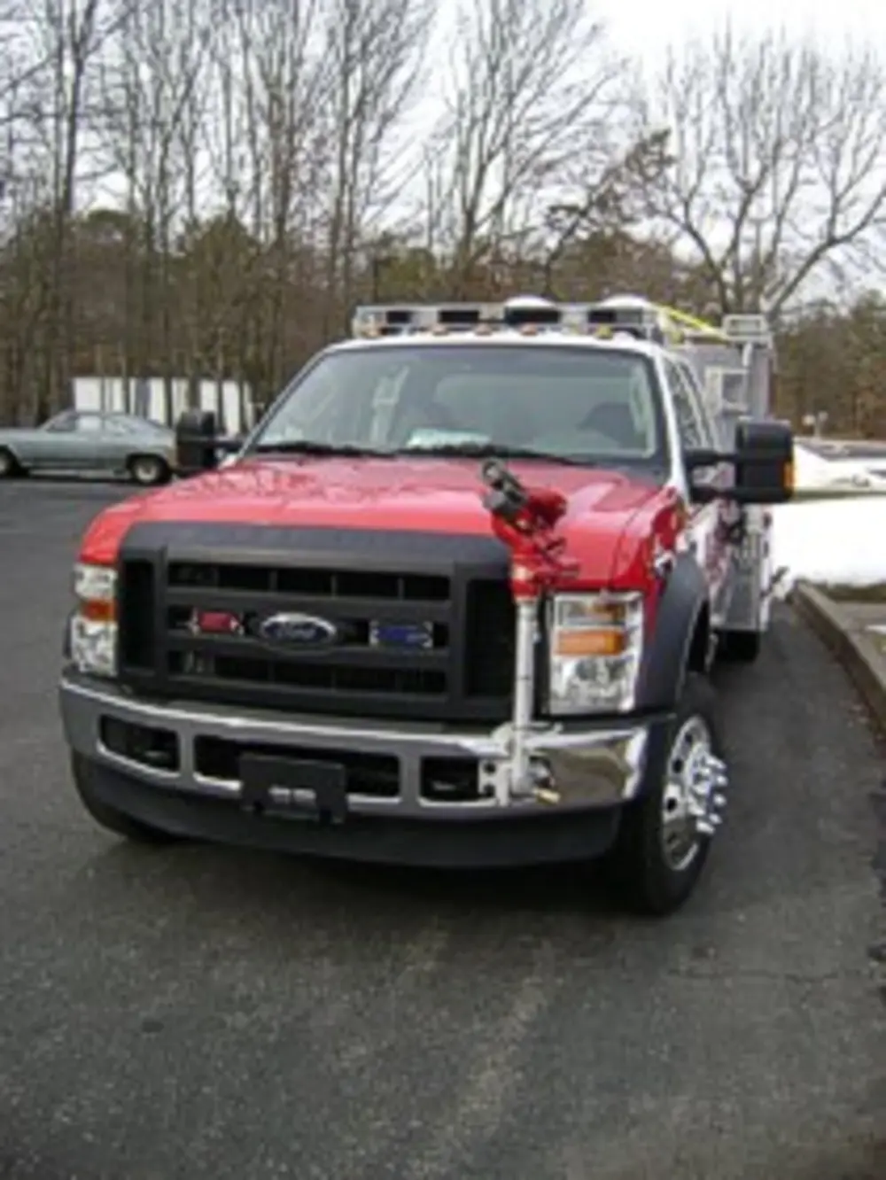Exterior view of small fire truck showing cab, body compartments, and wheel/tire area.