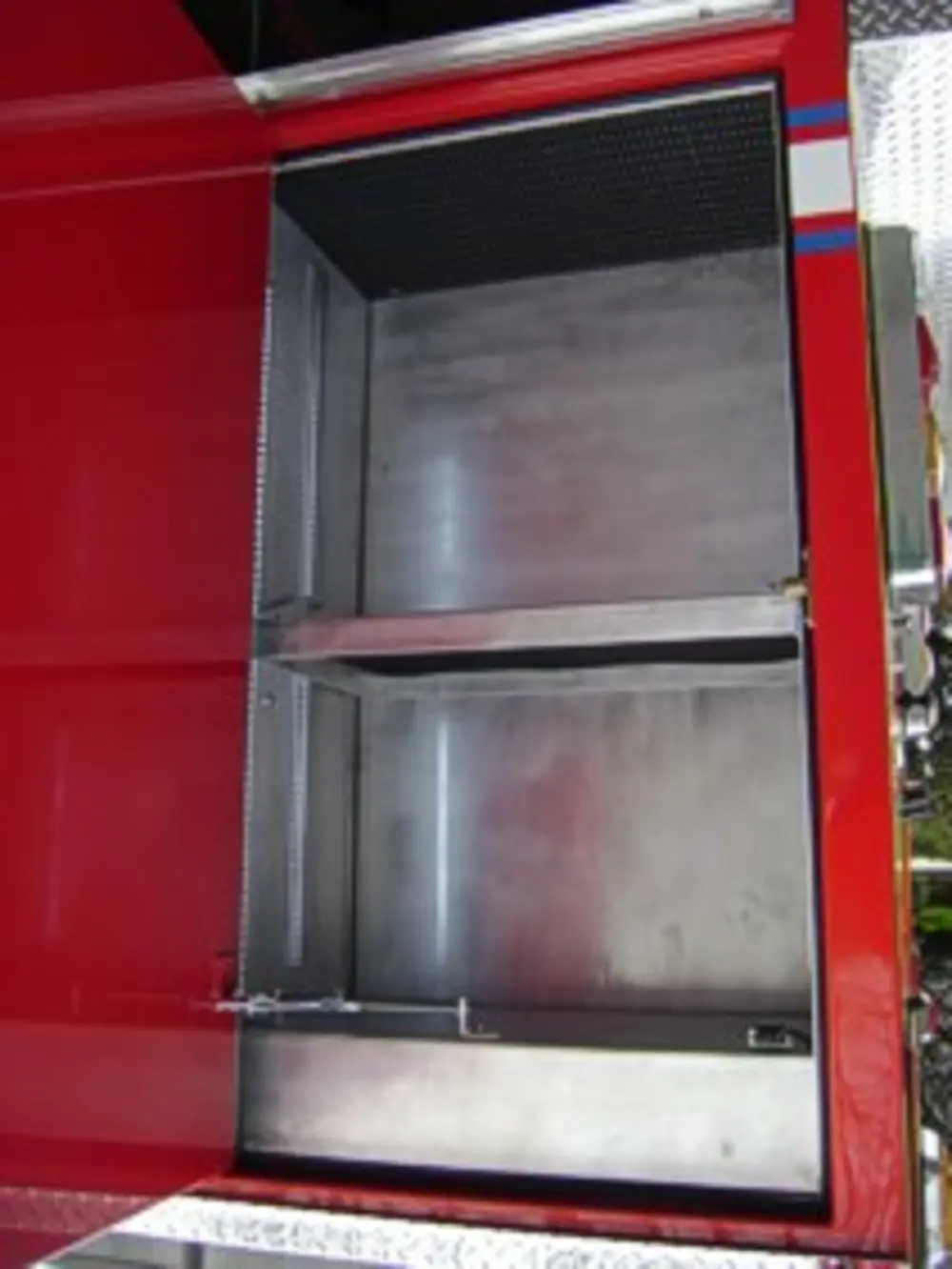 Exterior view of small fire truck showing cab, body compartments, and wheel/tire area.