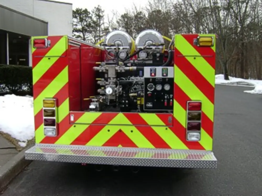 Exterior view of small fire truck showing cab, body compartments, and wheel/tire area.