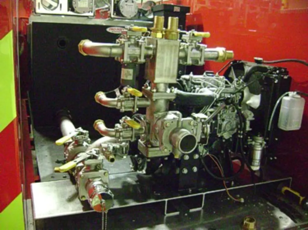 Exterior view of small fire truck showing cab, body compartments, and wheel/tire area.