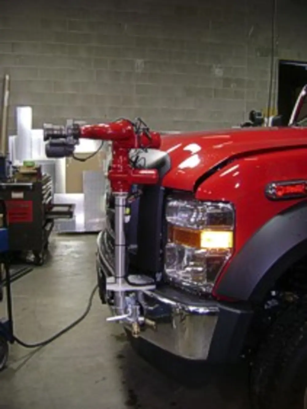 Exterior view of small fire truck showing cab, body compartments, and wheel/tire area.