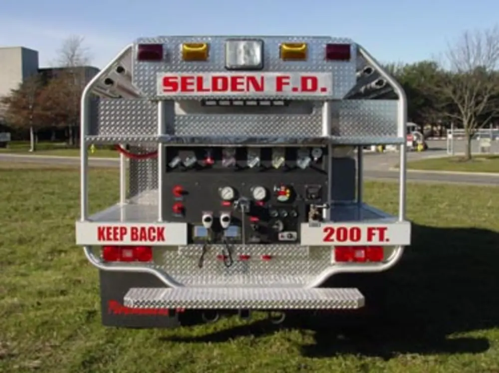 Exterior view of small fire truck showing cab, body compartments, and wheel/tire area.