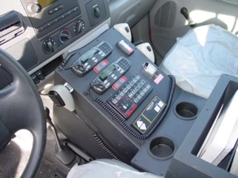 Exterior view of small fire truck showing cab, body compartments, and wheel/tire area.