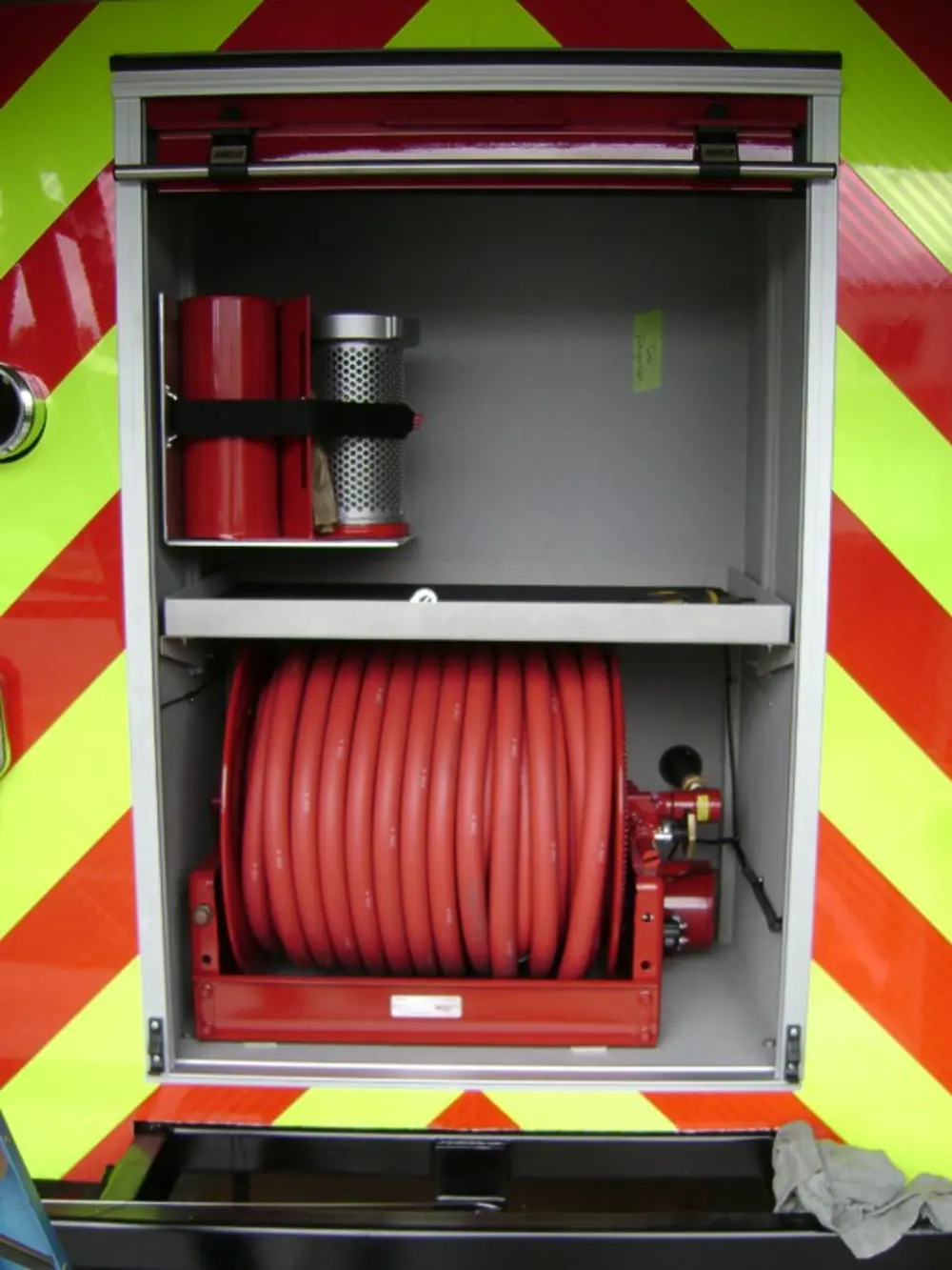 Exterior view of small fire truck showing cab, body compartments, and wheel/tire area.