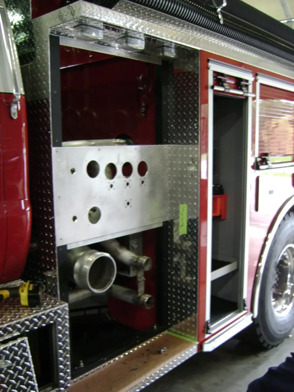 Exterior view of small fire truck showing cab, body compartments, and wheel/tire area.
