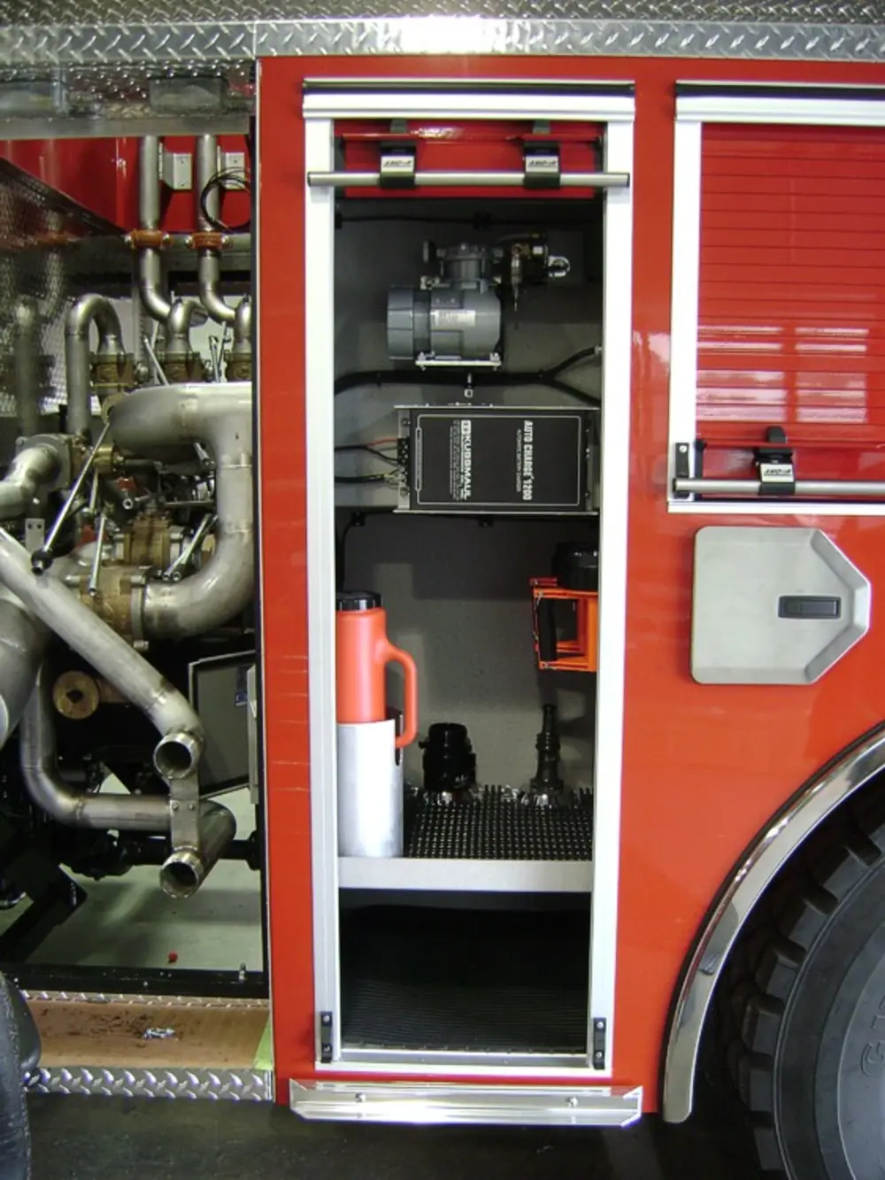 Exterior view of small fire truck showing cab, body compartments, and wheel/tire area.