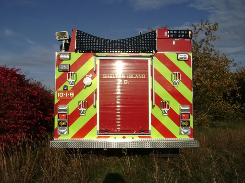 Exterior view of small fire truck showing cab, body compartments, and wheel/tire area.