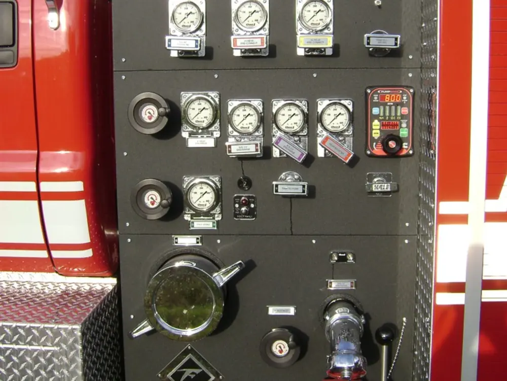 Exterior view of small fire truck showing cab, body compartments, and wheel/tire area.