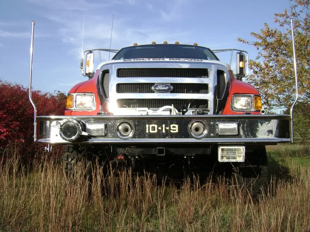 Exterior view of small fire truck showing cab, body compartments, and wheel/tire area.
