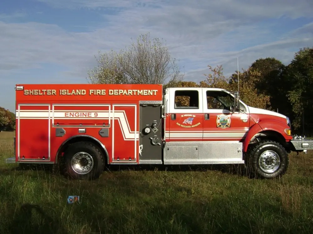 Exterior view of small fire truck showing cab, body compartments, and wheel/tire area.