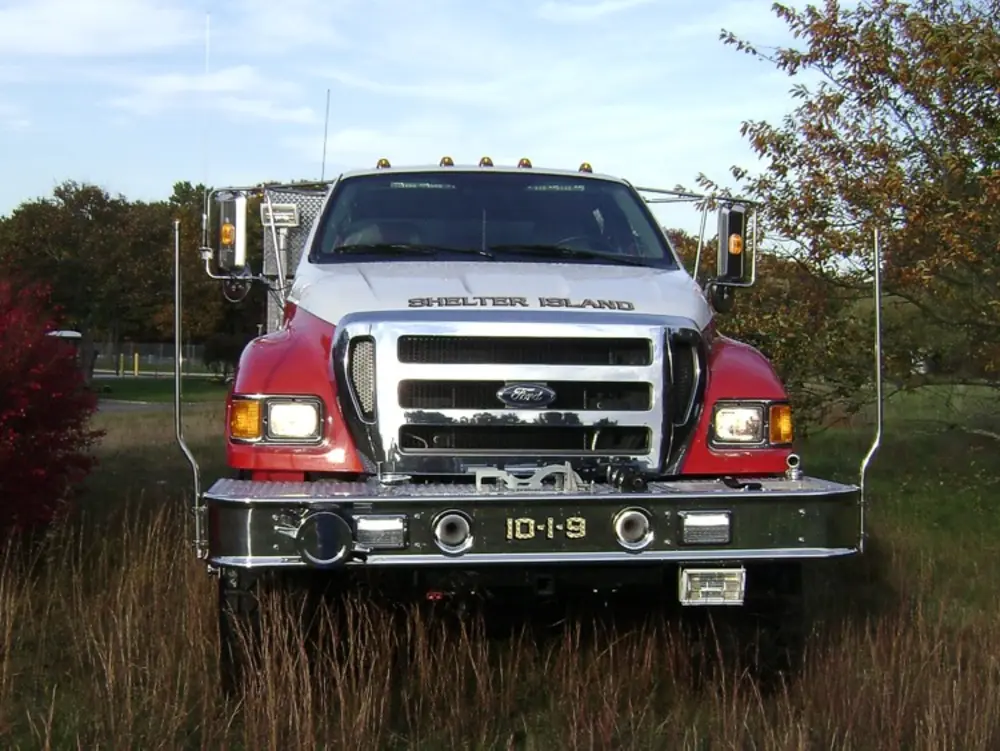 Exterior view of small fire truck showing cab, body compartments, and wheel/tire area.
