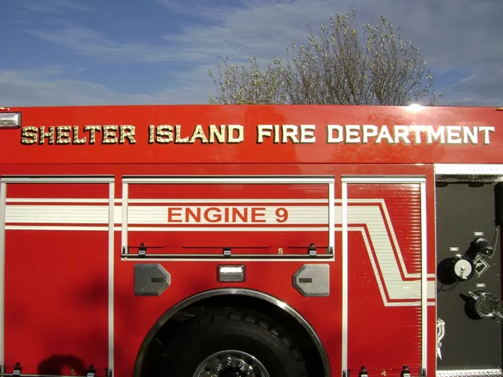 Exterior view of small fire truck showing cab, body compartments, and wheel/tire area.