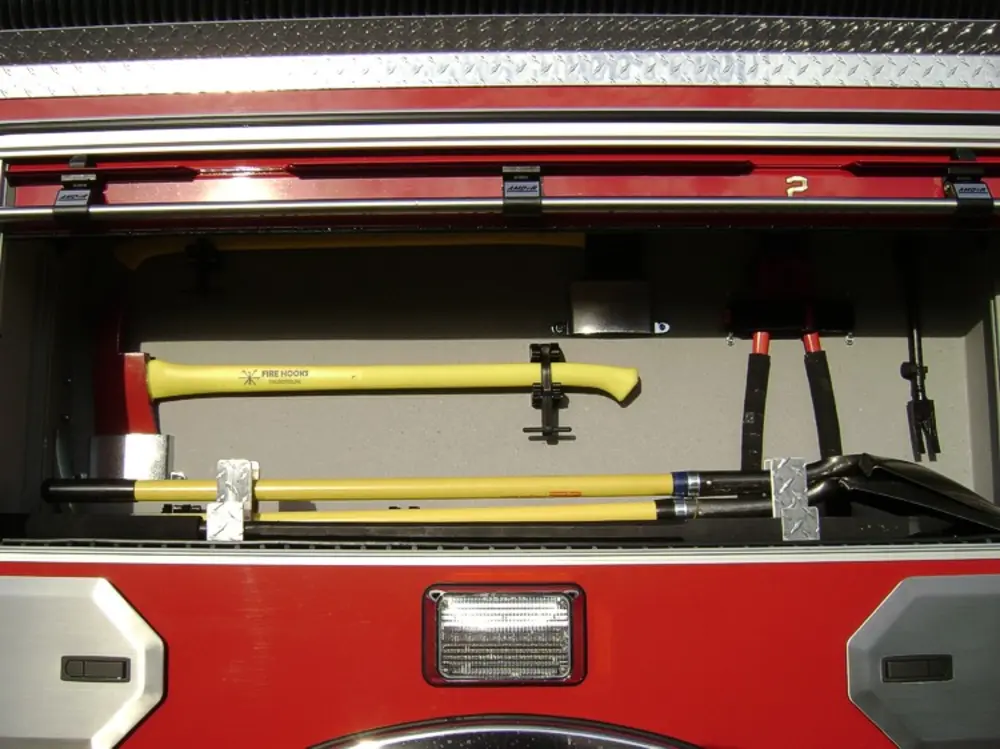 Exterior view of small fire truck showing cab, body compartments, and wheel/tire area.