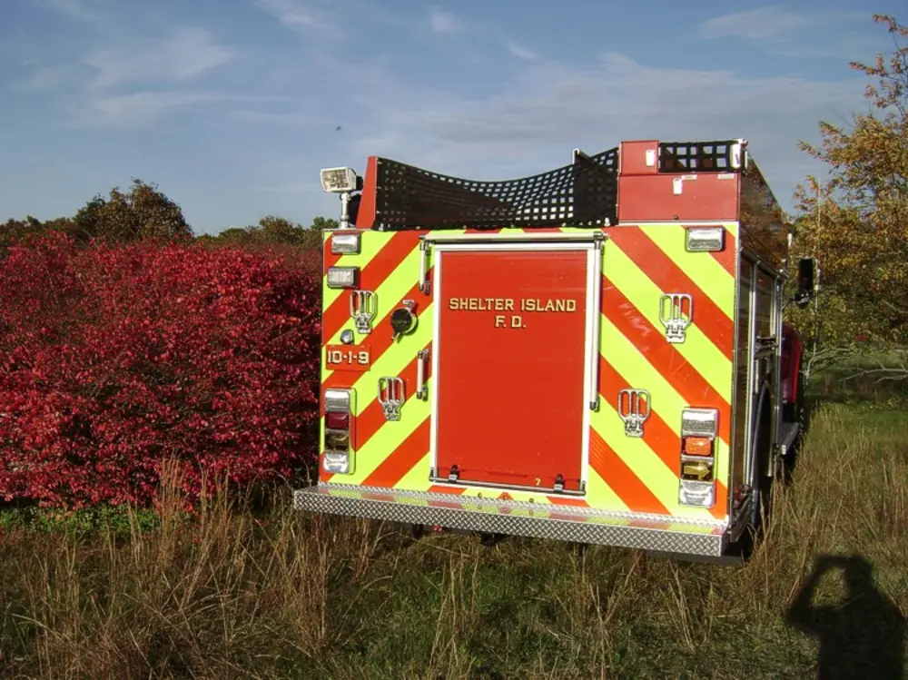 Exterior view of small fire truck showing cab, body compartments, and wheel/tire area.