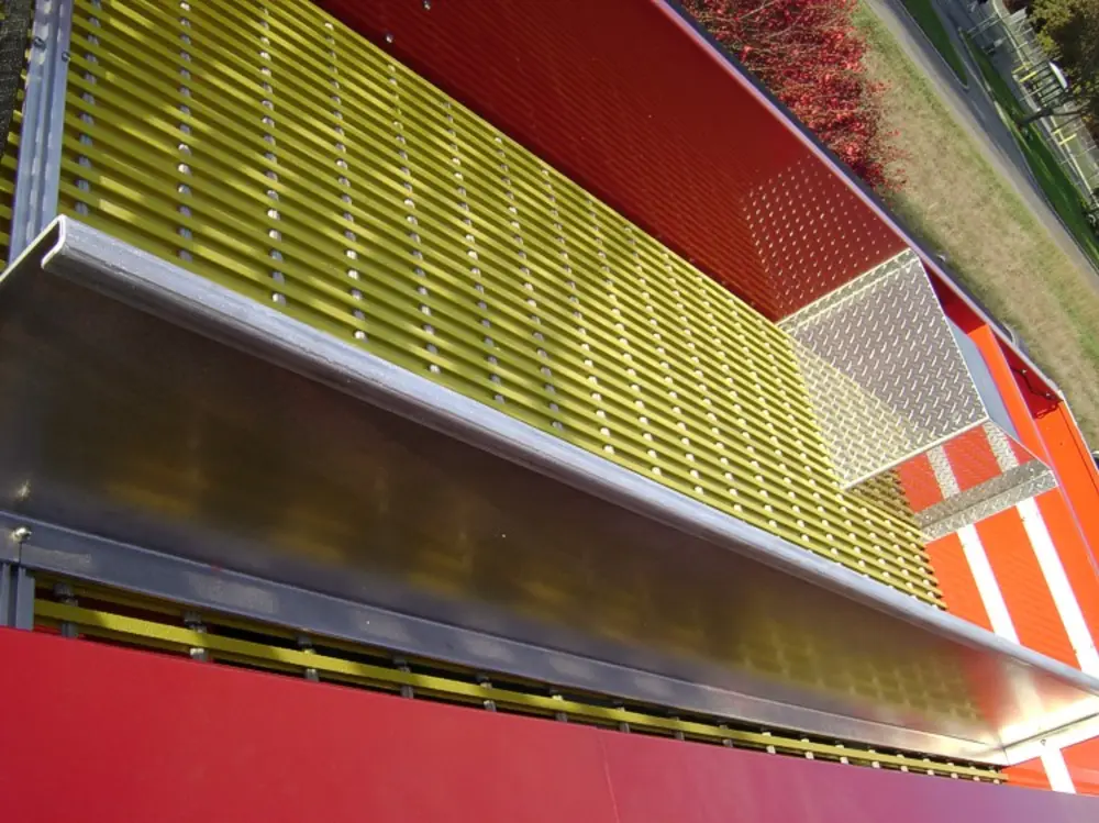 Exterior view of small fire truck showing cab, body compartments, and wheel/tire area.