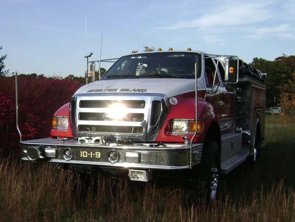 Exterior view of small fire truck showing cab, body compartments, and wheel/tire area.
