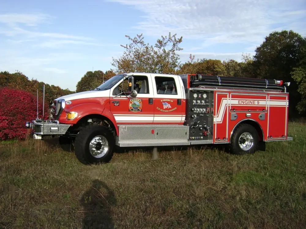 Exterior view of small fire truck showing cab, body compartments, and wheel/tire area.