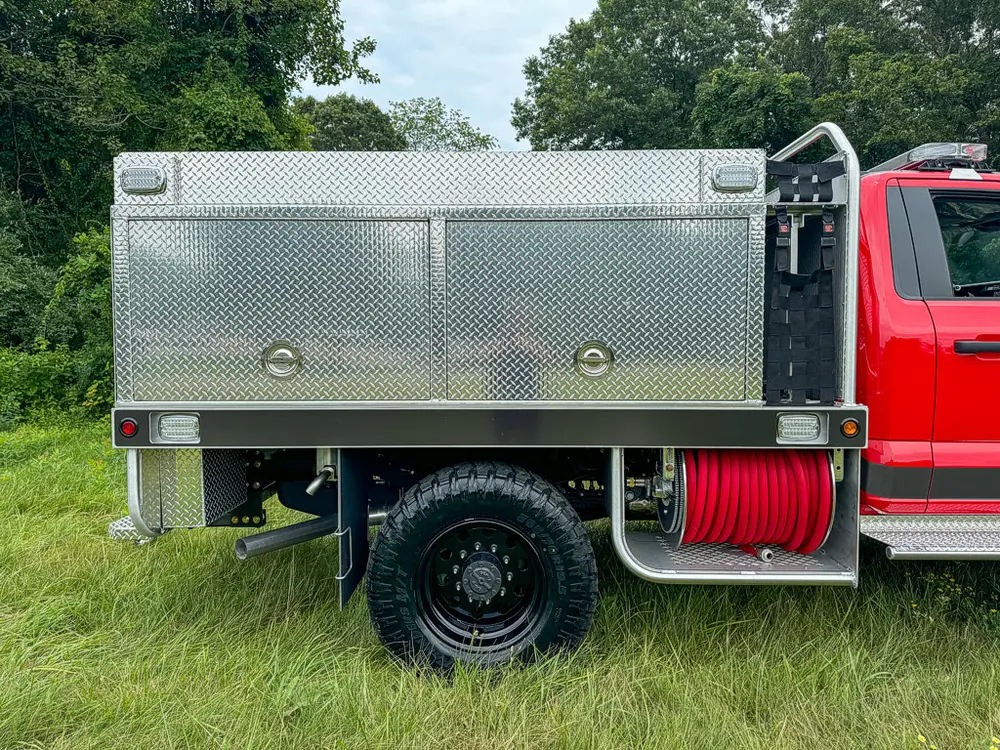 Right-side utility body close-up with closed compartment doors and hose reel.