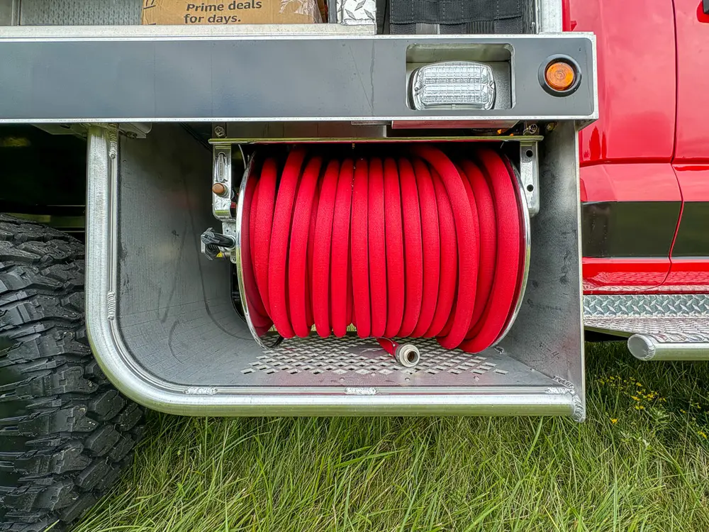 Close-up of red hose reel mounted in lower side compartment.