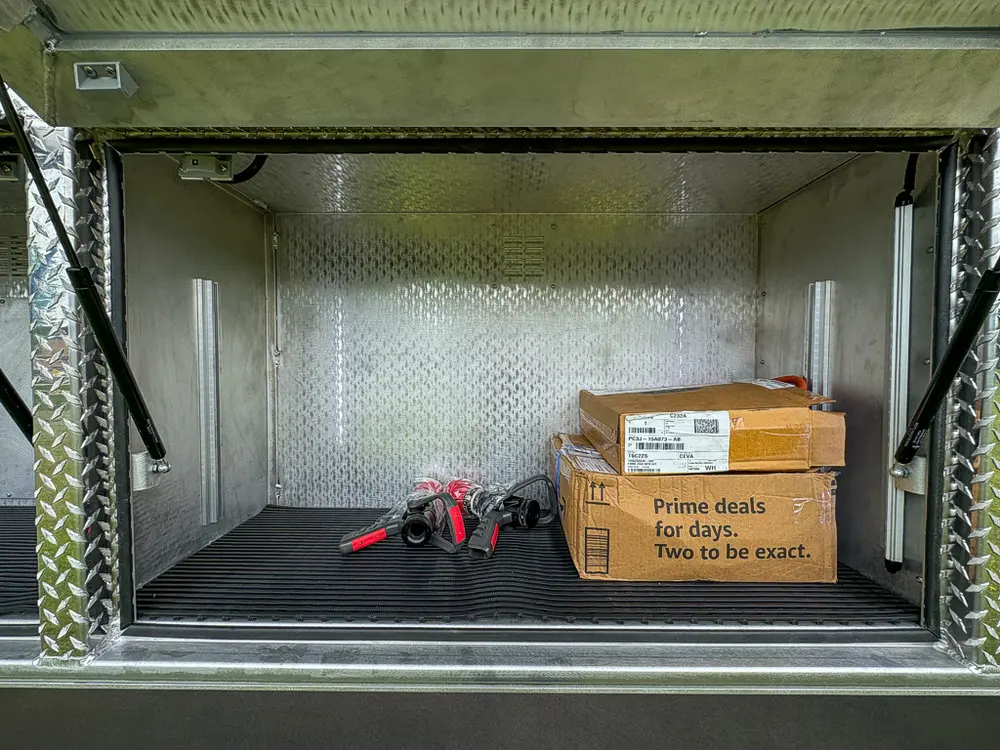 Open side compartment with box and small tools on compartment floor.