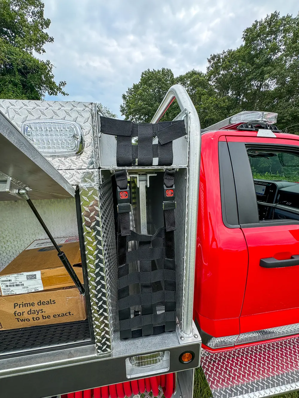 Open vertical side rack behind cab with mounted red equipment packs.